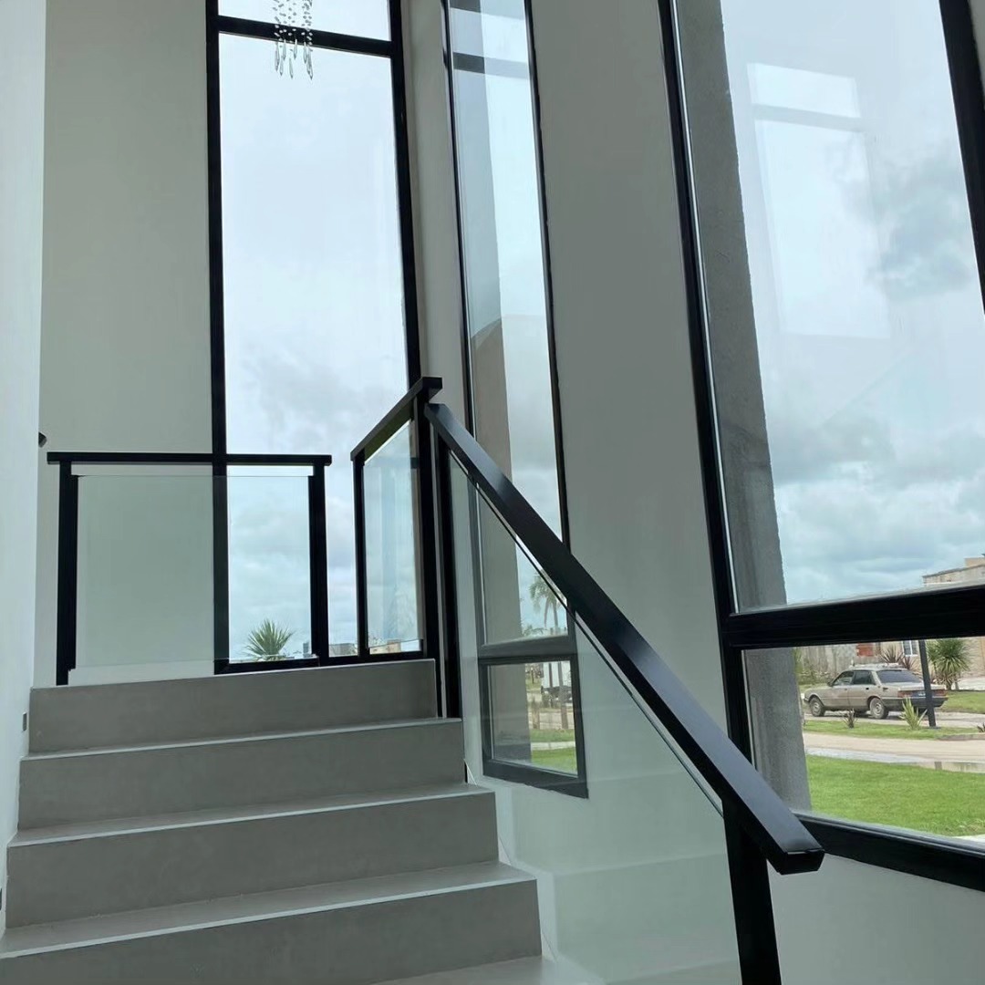 Casa terminada con doble altura vidriada, escalera de hormigón y baranda de vidrio